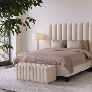 Bente bänk från Eichholtz framför en säng i ett sovrum.